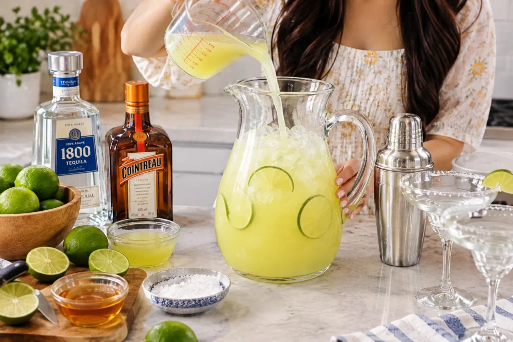 Preparing my homemade margarita pitcher with fresh lime juice, ice, and cocktail ingredients.